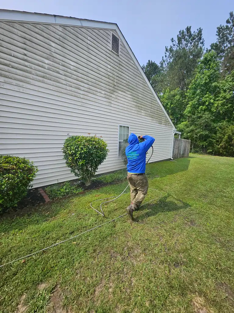 House exterior being pressure washed in a side yard