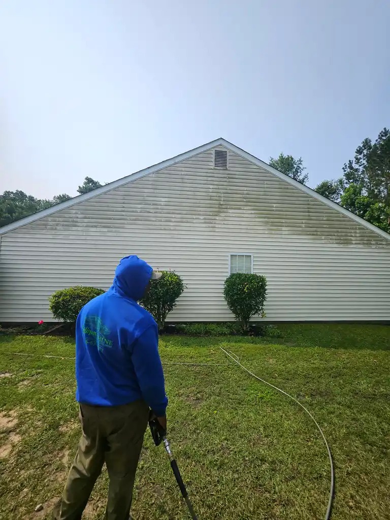 Worker pressure washing a house exterior